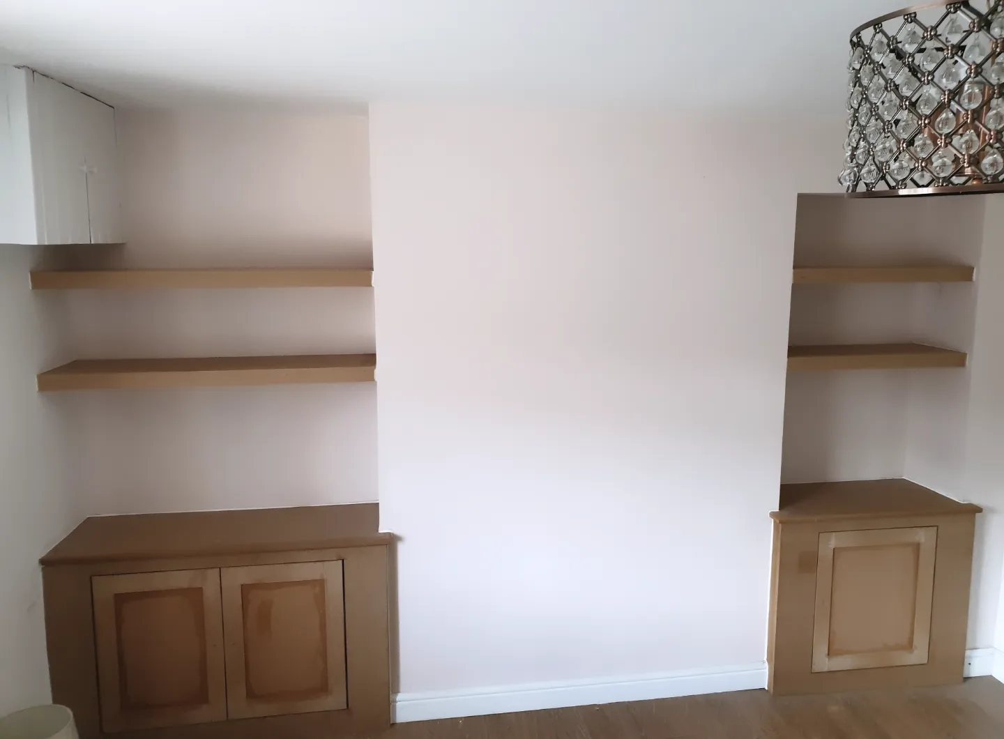Alcove cupboards and floating shelves either side of a chimney breast, before painting