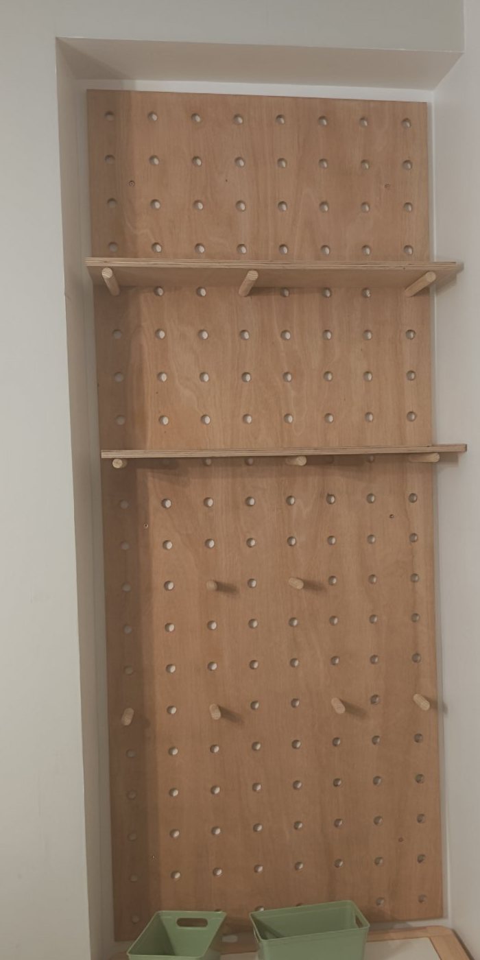 Plywood pegboard wall with shelves built into an alcove